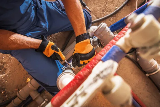 Plumber in work gloves connecting new insulated PEX water lines